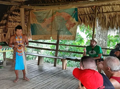 Embera guide in traditional dress talking to visitors under a thatched roof on a panama monkey island day tour